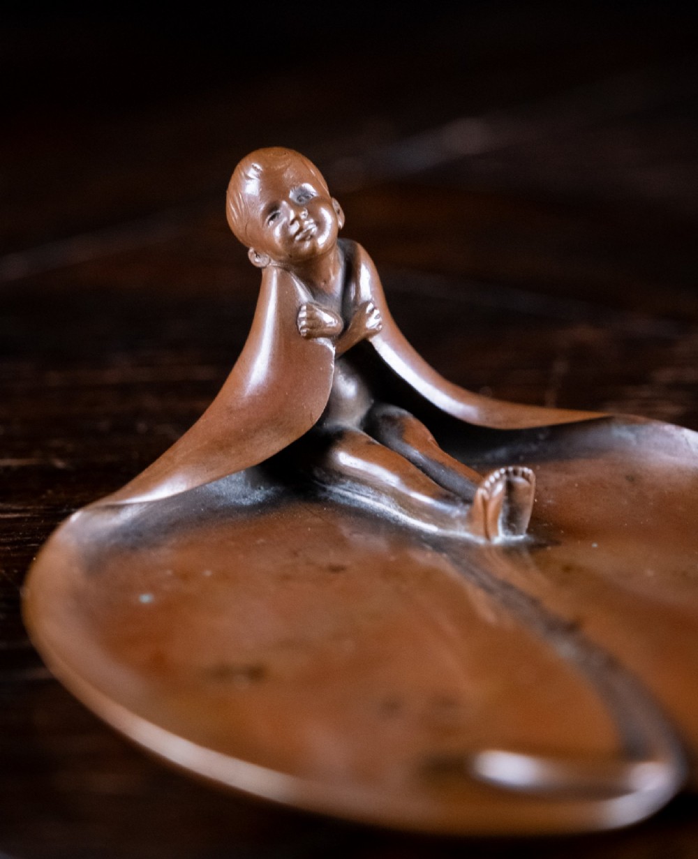 A pair of small, patinated bronze leaf-shaped dishes, each featuring a sculpted figure of a child seated at the folded edge. View IV
