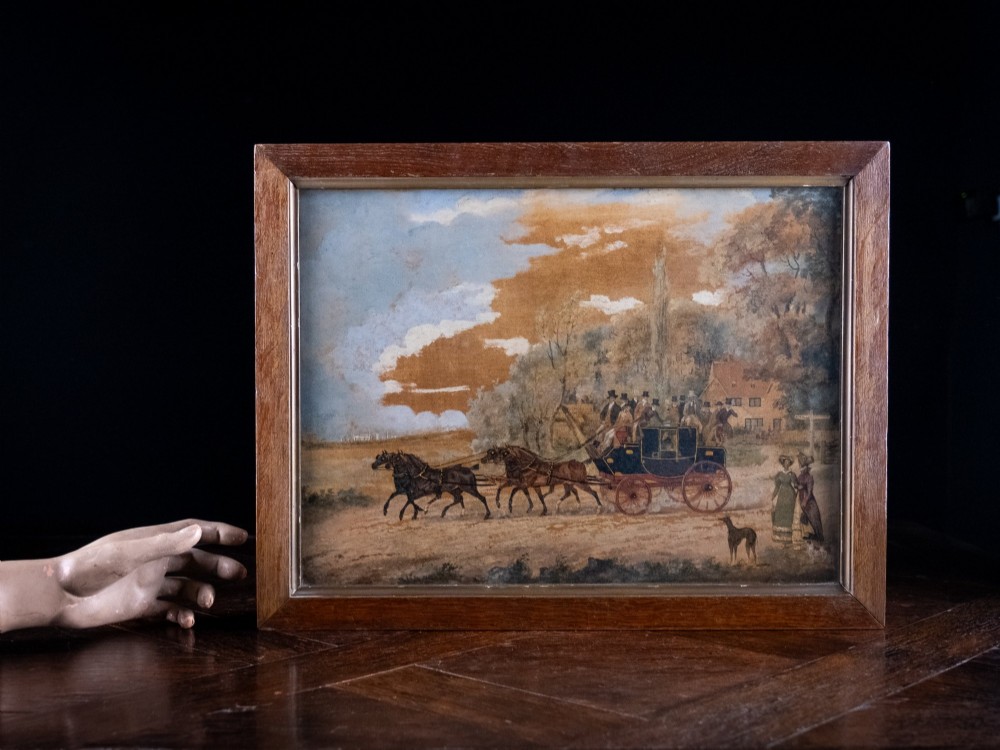 A framed 19th-century oil painting on board depicting a horse-drawn stagecoach travelling along a rural dirt road past figures and a cottage under a cloudy sky. View X