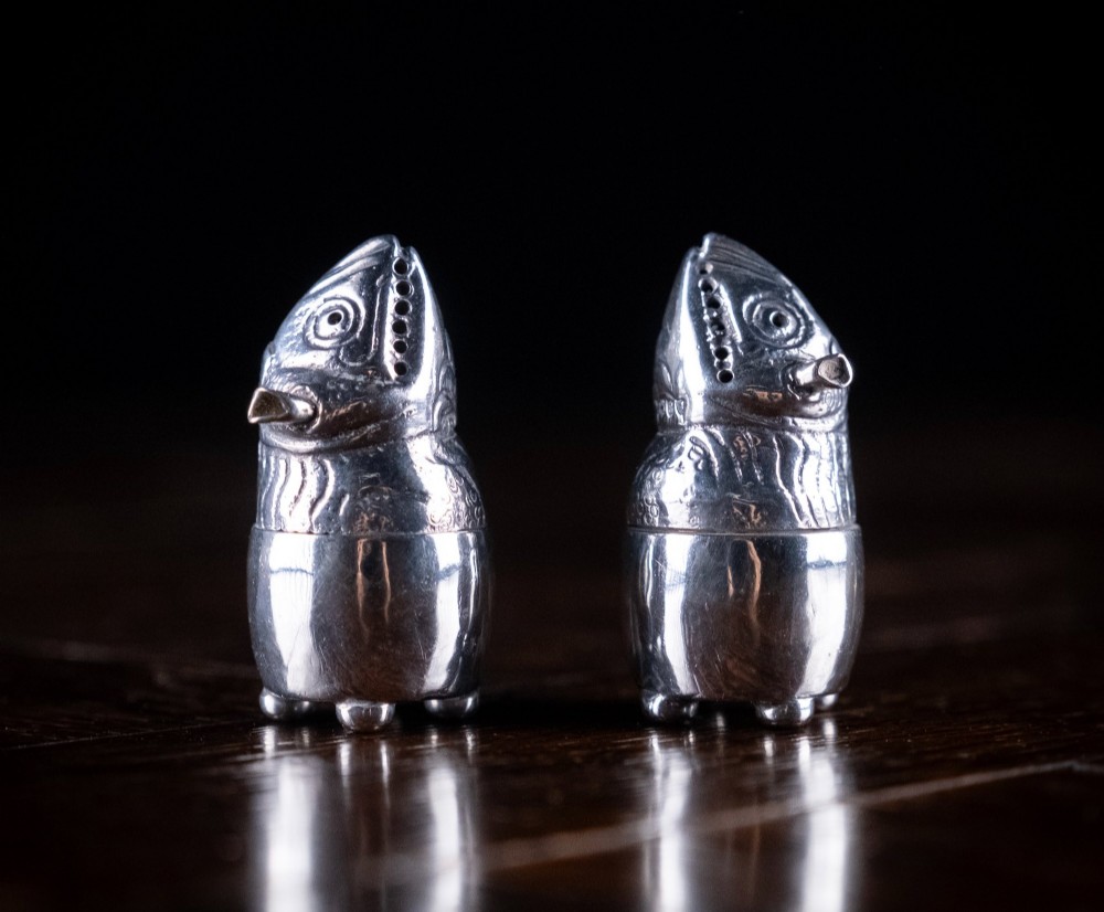 A pair of Victorian sterling silver novelty pepper pots shaped as grotesque birds smoking pipes.