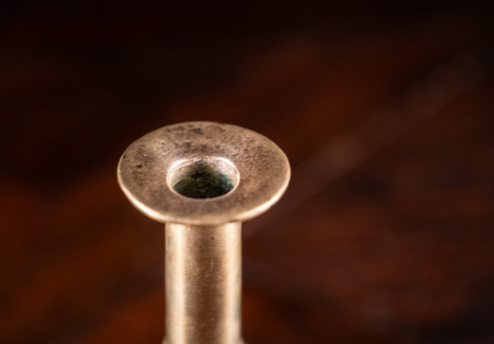 A pair of 18th-century cast brass candlesticks featuring turned baluster stems, push-up ejector mechanisms, and scalloped circular bases. View VII