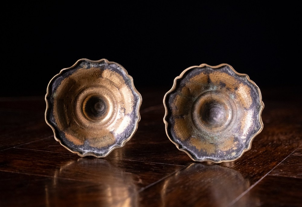 A pair of 18th-century cast brass candlesticks featuring turned baluster stems, push-up ejector mechanisms, and scalloped circular bases. View IX