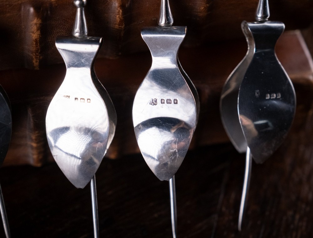 A set of four solid sterling silver lemon wedge squeezers featuring hinged mechanical presses and English hallmarks. View II