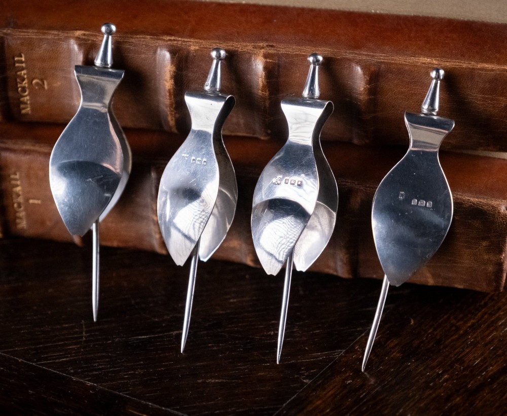 A set of four solid sterling silver lemon wedge squeezers featuring hinged mechanical presses and English hallmarks. View III