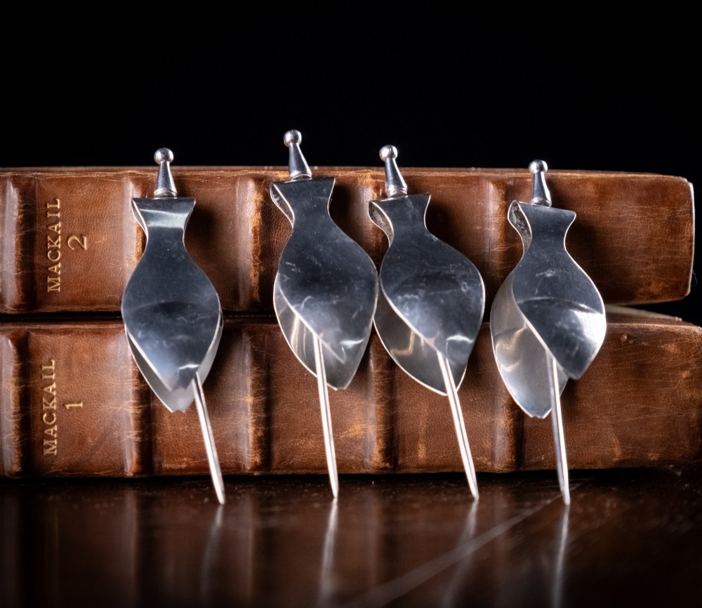 A set of four solid sterling silver lemon wedge squeezers featuring hinged mechanical presses and English hallmarks. View IV