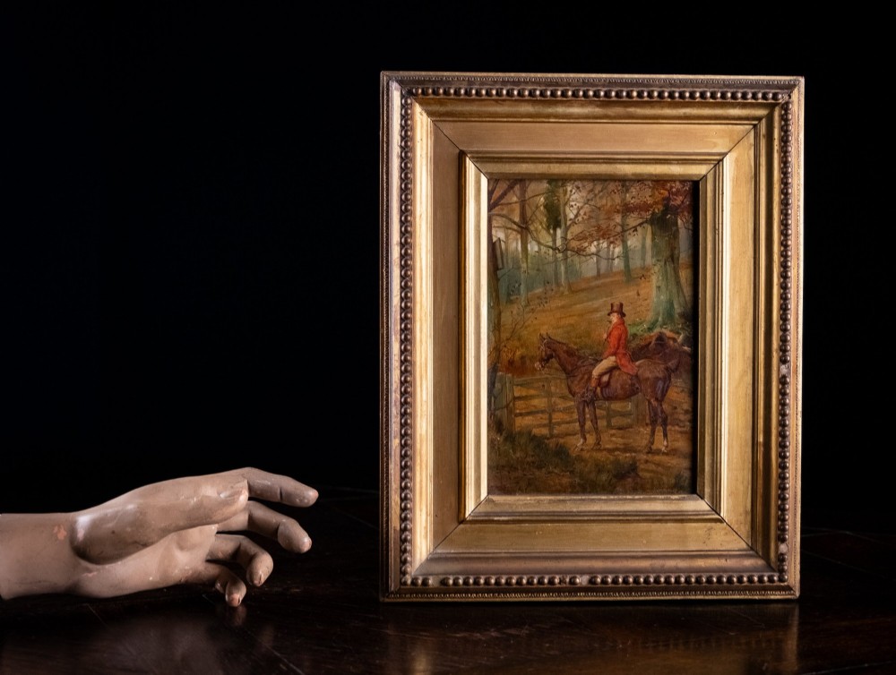 A 19th-century oil painting on panel depicting a gentleman in a red hunting coat atop a horse next to a timber gate in autumn woods. View V