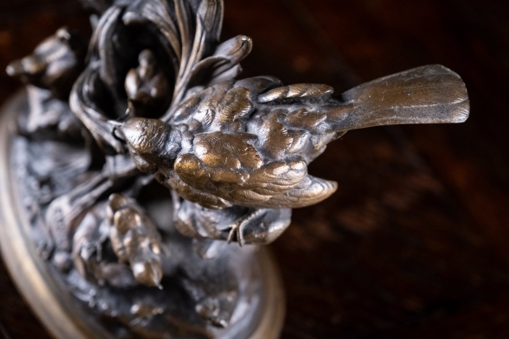 A 19th-century dark patinated bronze sculpture depicting parent birds and fledglings surrounding a foliage nest on an oval base. View V