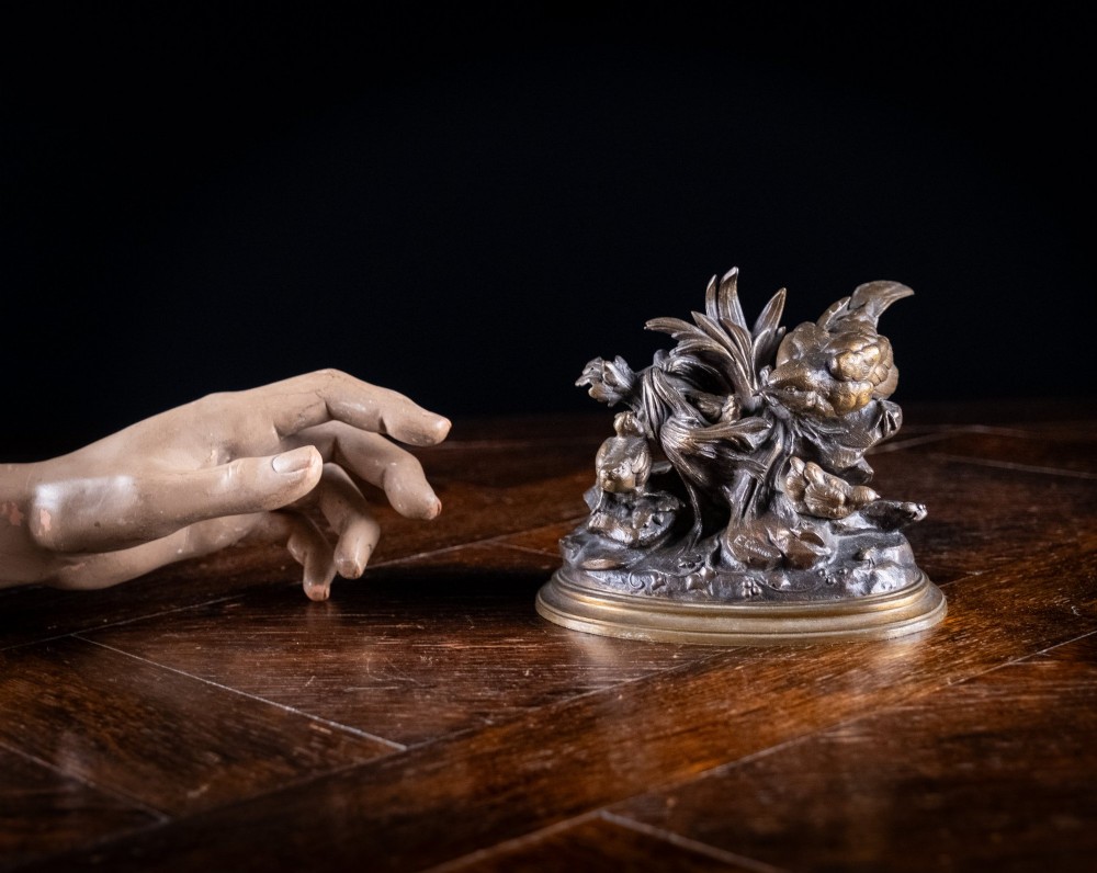 A 19th-century dark patinated bronze sculpture depicting parent birds and fledglings surrounding a foliage nest on an oval base. View X