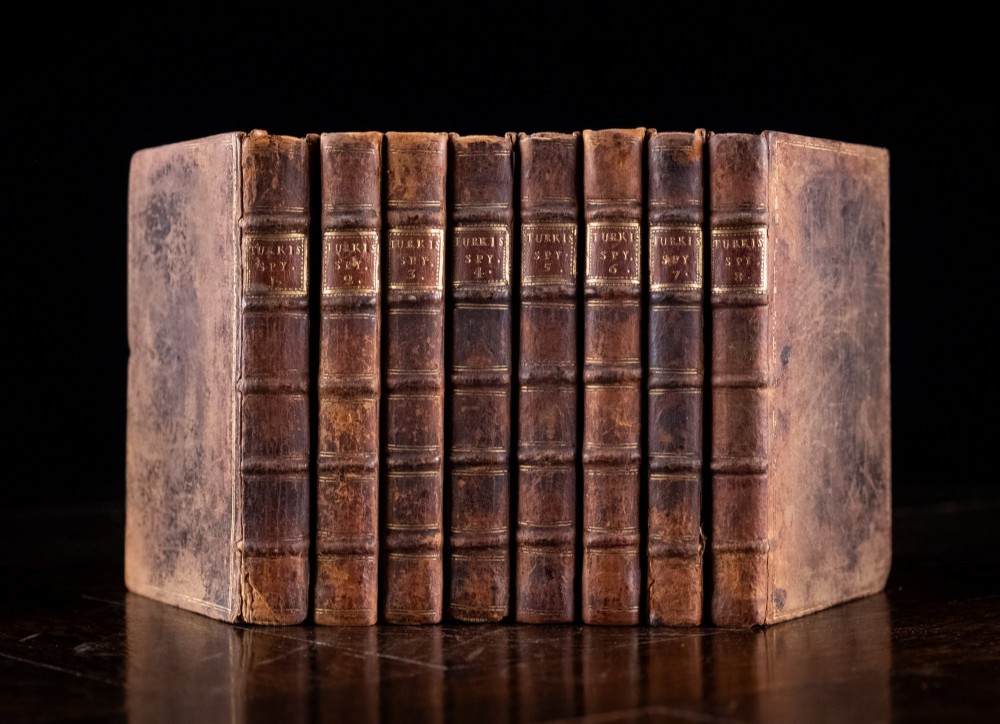 An eight-volume set of 18th-century leather-bound books standing upright with visible raised spine bands and gilt titles.