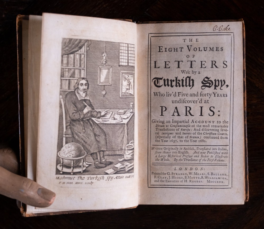 An eight-volume set of 18th-century leather-bound books standing upright with visible raised spine bands and gilt titles. View VII