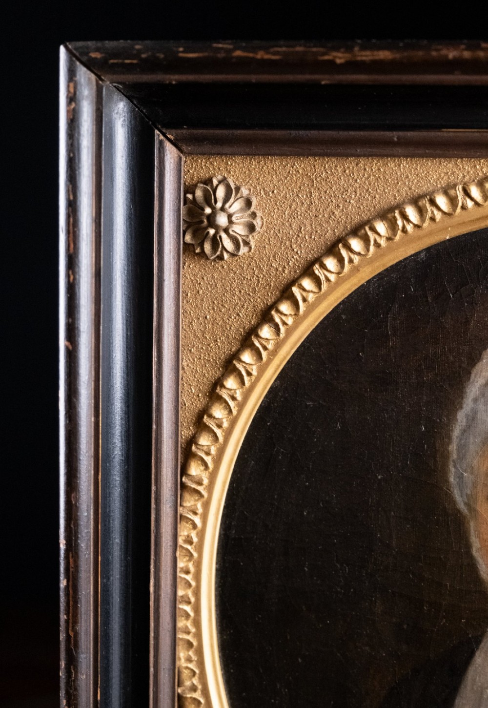 An 18th-century oil painting depicting a lady in a white lace cap and dark garment, framed within a gilded oval slip set inside a rectangular dark wooden frame. View VIII