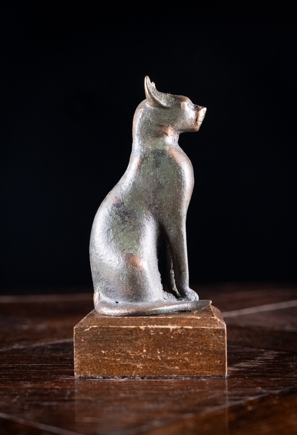 A patinated bronze sculpture of an upright seated Egyptian cat mounted on a rectangular wooden plinth base. View VI