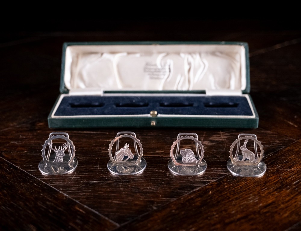 A set of four sterling silver animal-themed menu holders featuring a stag, horse, dog, and hare, presented inside a fitted green display box. View II