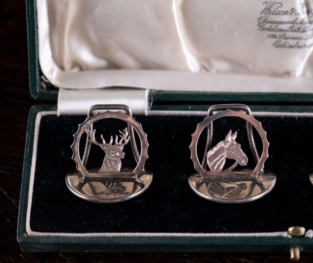 A set of four sterling silver animal-themed menu holders featuring a stag, horse, dog, and hare, presented inside a fitted green display box. View VII