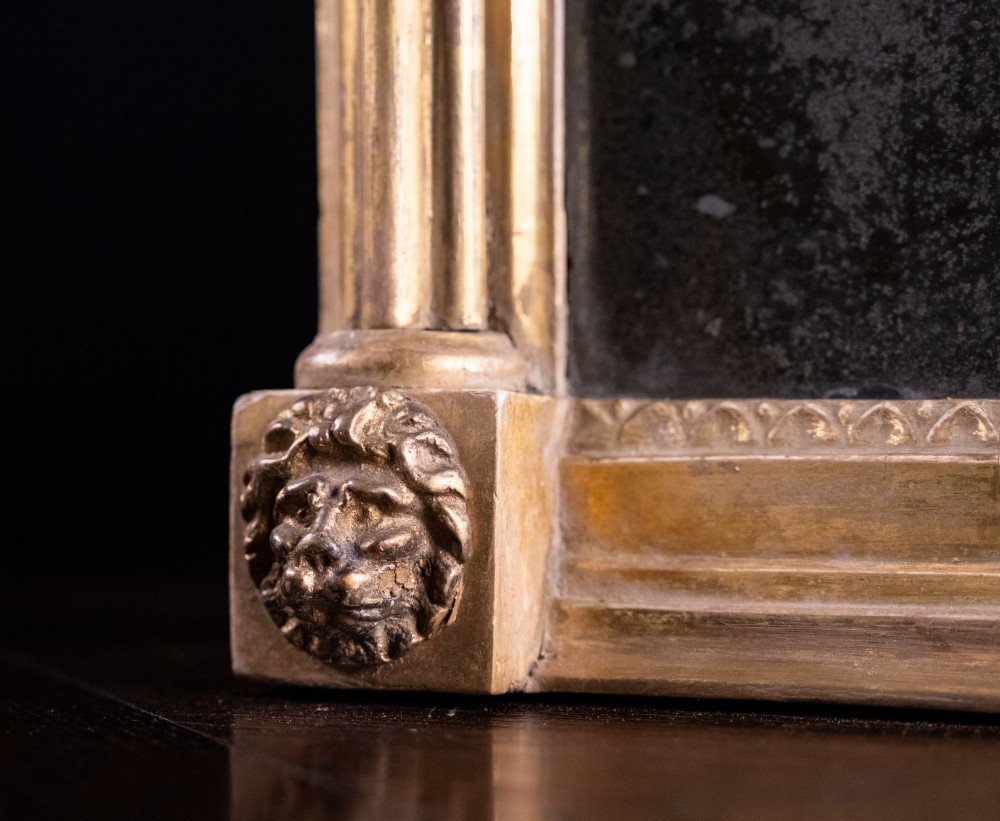 A large Regency style painted and gilded pier mirror featuring classical fluted columns, lion mask corner accents, a ball-ornament cornice, and distressed mirror glass. View VII