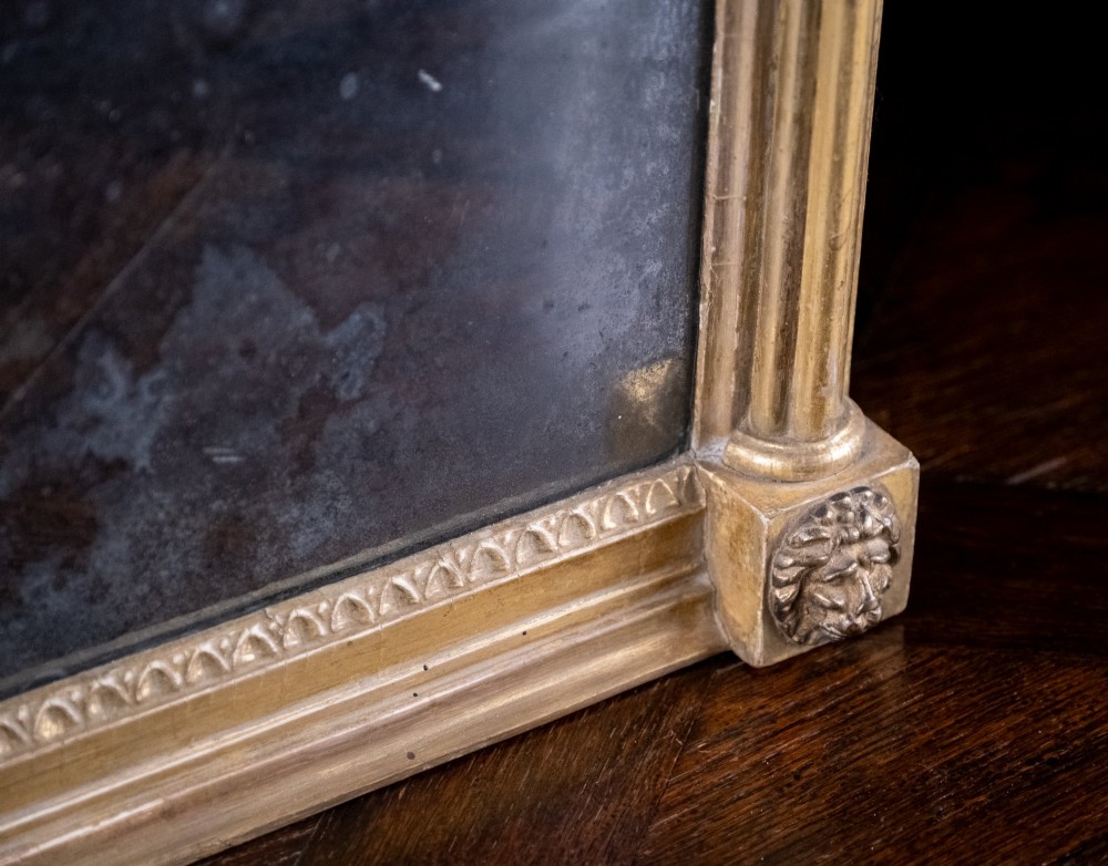 A large Regency style painted and gilded pier mirror featuring classical fluted columns, lion mask corner accents, a ball-ornament cornice, and distressed mirror glass. View XII