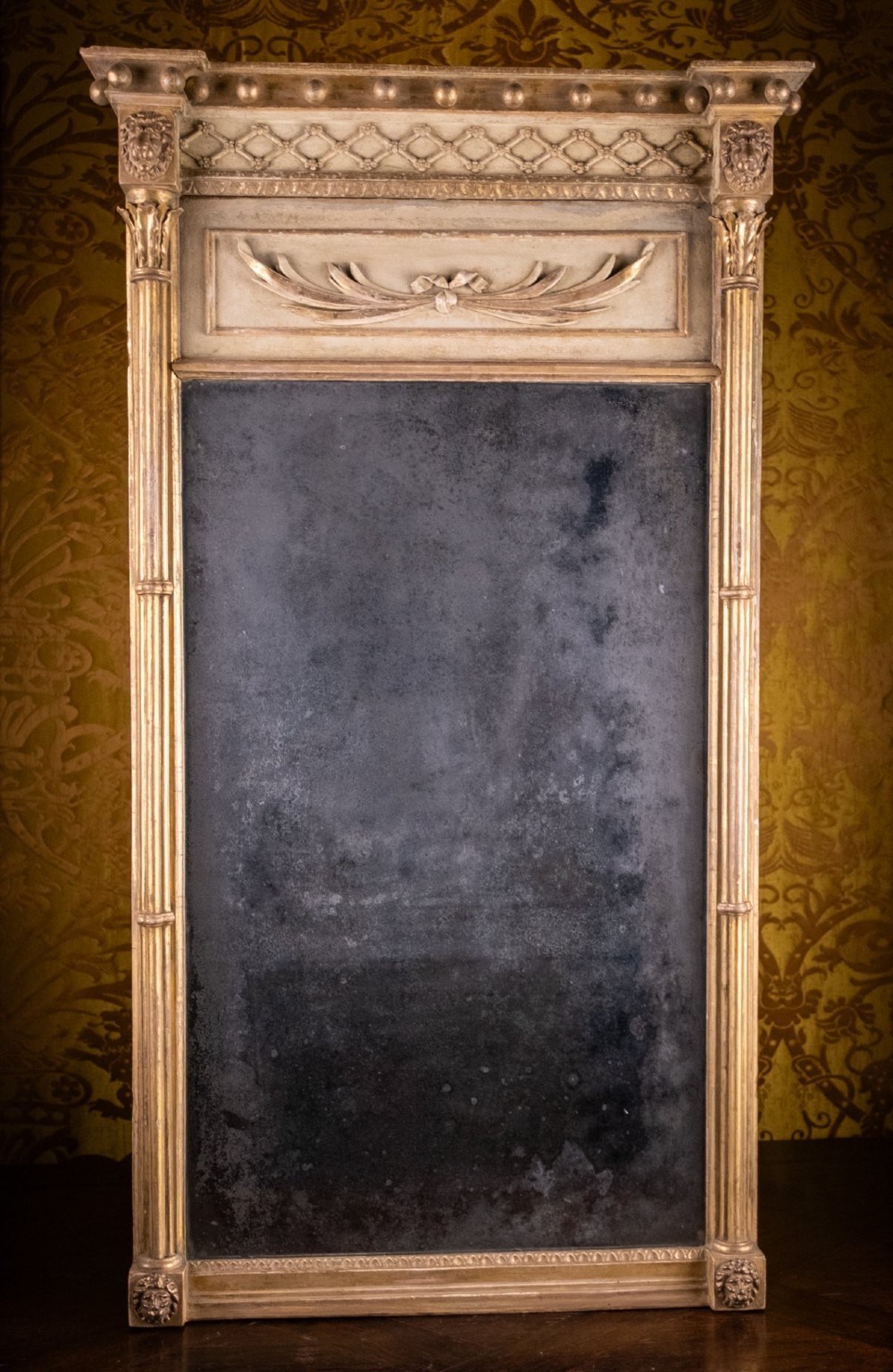 A large Regency style painted and gilded pier mirror featuring classical fluted columns, lion mask corner accents, a ball-ornament cornice, and distressed mirror glass. View XIV