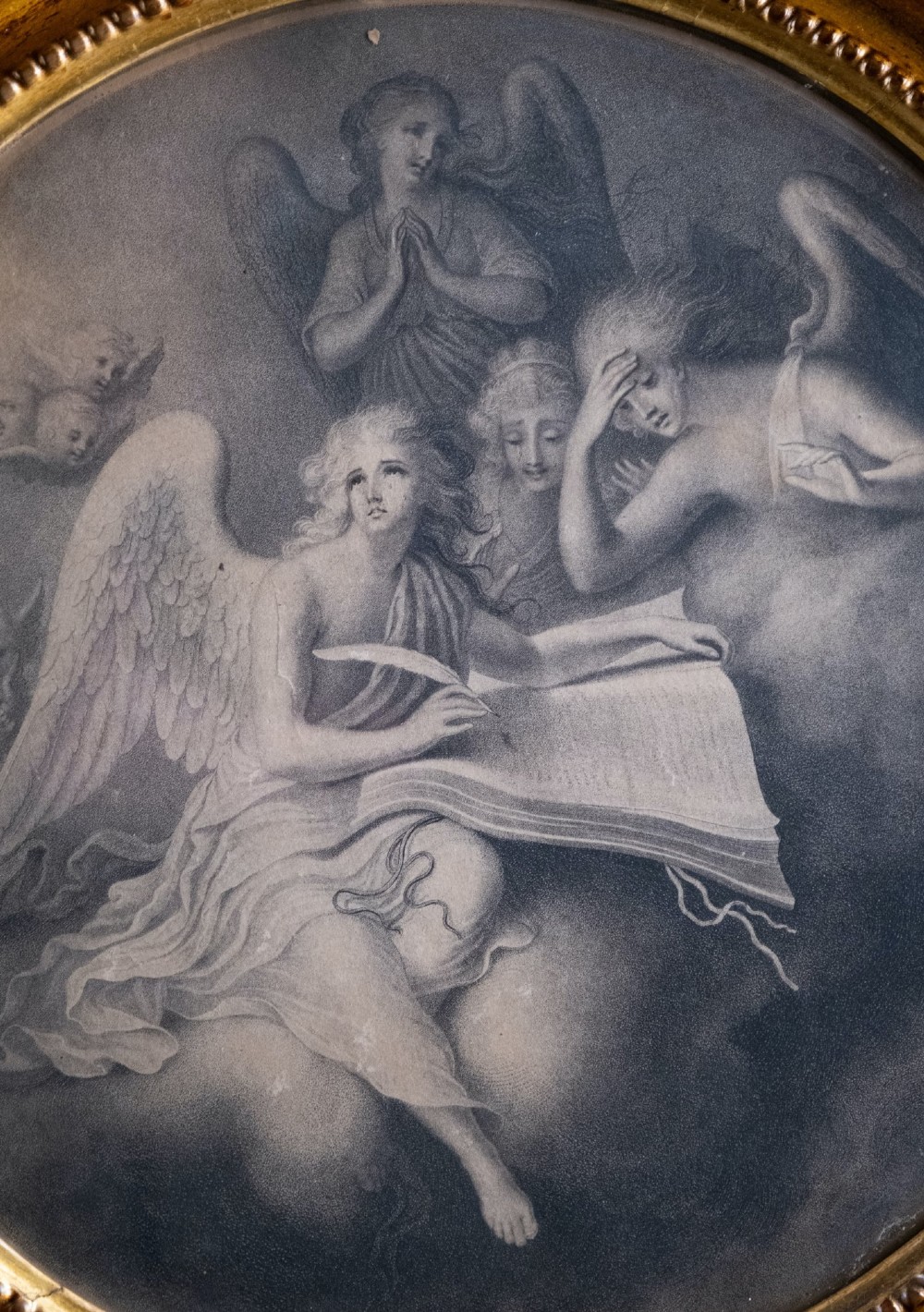 An eighteenth-century circular monochrome engraving depicting winged angels among clouds, set within a carved circular giltwood frame. View III