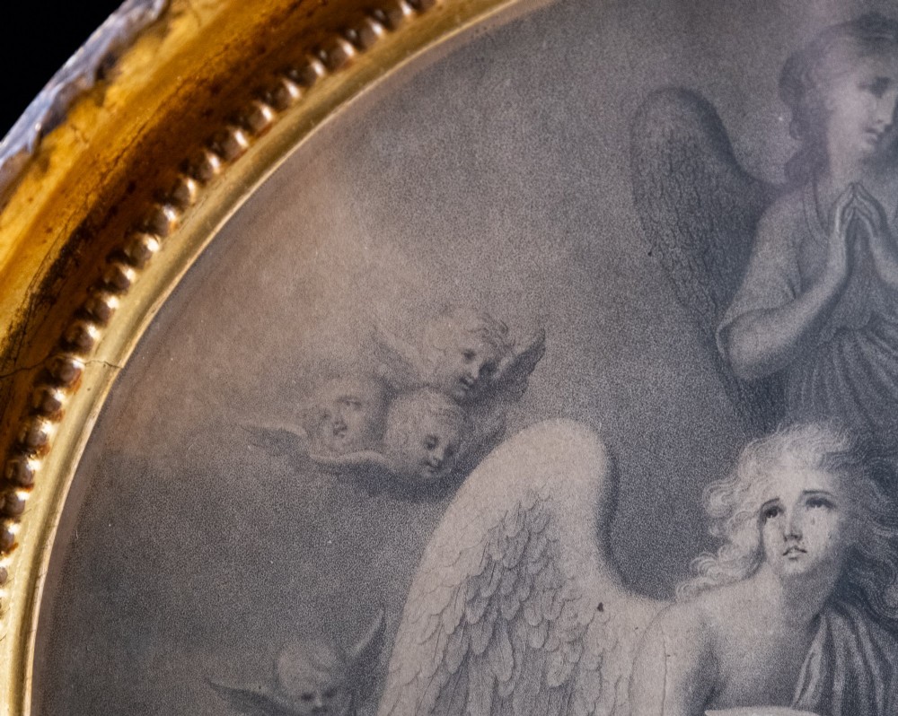An eighteenth-century circular monochrome engraving depicting winged angels among clouds, set within a carved circular giltwood frame. View V