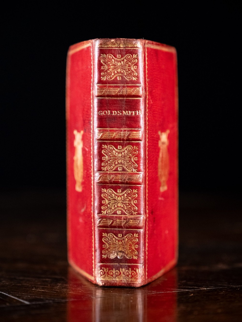 An 1821 miniature book bound in red leather featuring gilt spine tooling, raised bands, and gold lettering.