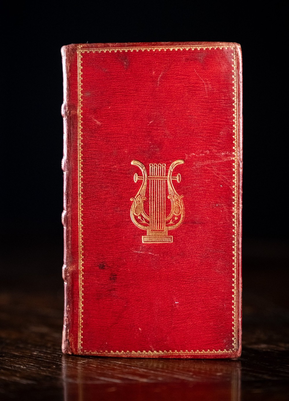 An 1821 miniature book bound in red leather featuring gilt spine tooling, raised bands, and gold lettering. View III
