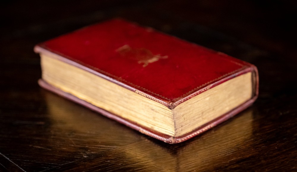 An 1821 miniature book bound in red leather featuring gilt spine tooling, raised bands, and gold lettering. View V