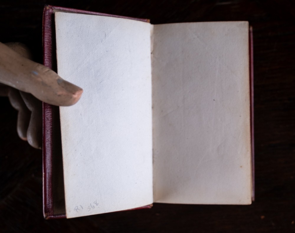 An 1821 miniature book bound in red leather featuring gilt spine tooling, raised bands, and gold lettering. View VII
