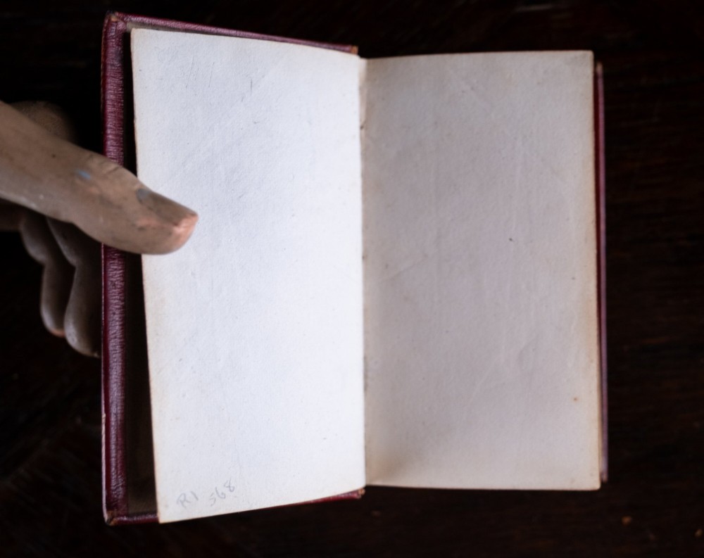 An 1821 miniature book bound in red leather featuring gilt spine tooling, raised bands, and gold lettering. View VIII