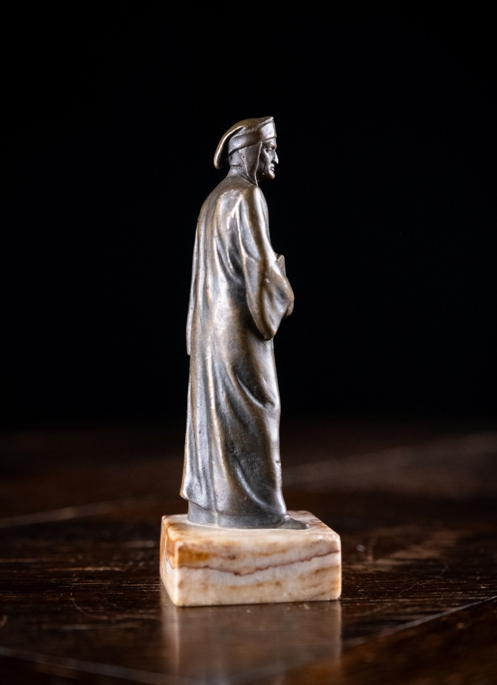 A nineteenth-century dark bronze statuette depicting the poet Dante Alighieri standing in long robes and holding a book, mounted on a square veined marble base. View V
