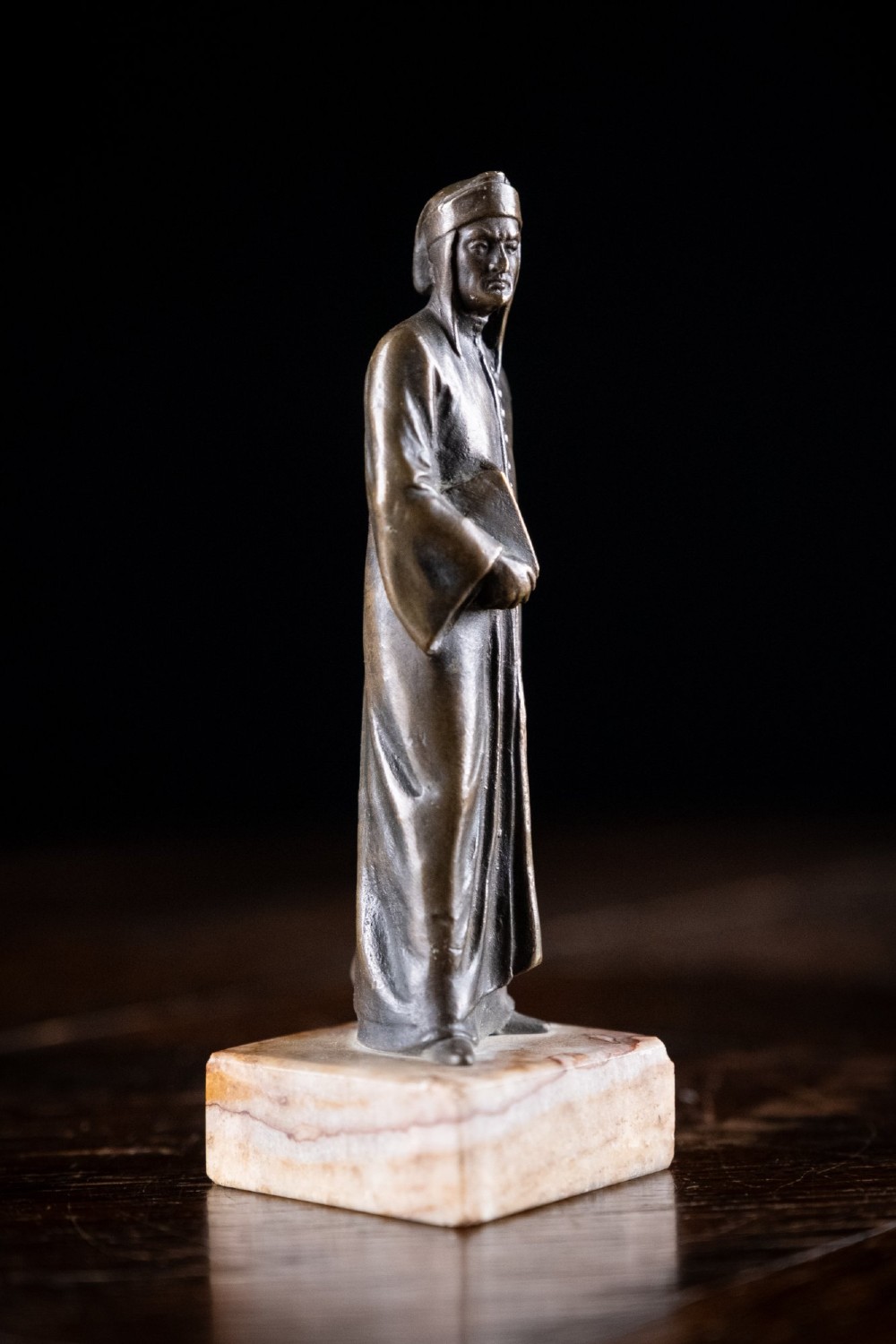 A nineteenth-century dark bronze statuette depicting the poet Dante Alighieri standing in long robes and holding a book, mounted on a square veined marble base. View VI