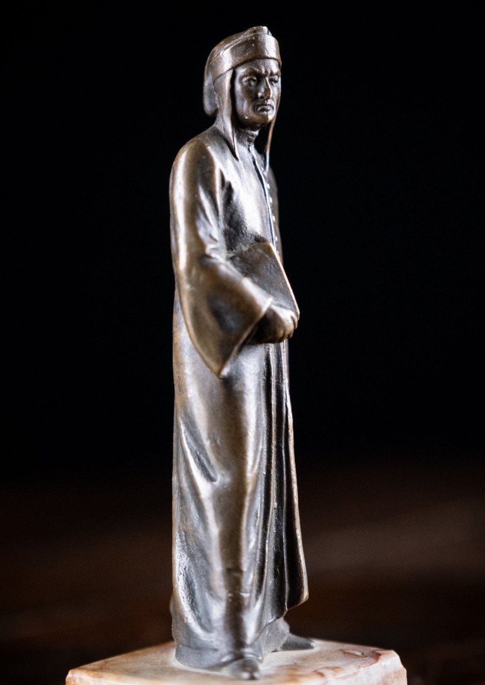 A nineteenth-century dark bronze statuette depicting the poet Dante Alighieri standing in long robes and holding a book, mounted on a square veined marble base. View VII