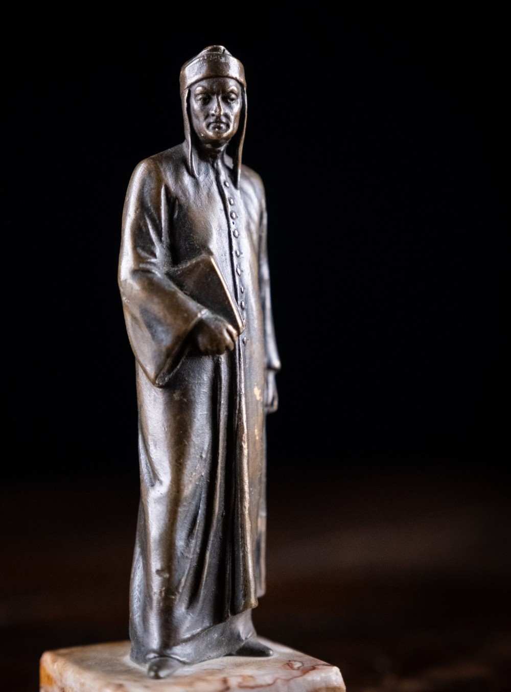 A nineteenth-century dark bronze statuette depicting the poet Dante Alighieri standing in long robes and holding a book, mounted on a square veined marble base. View VIII