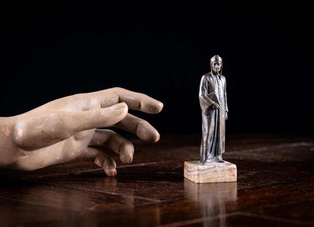 A nineteenth-century dark bronze statuette depicting the poet Dante Alighieri standing in long robes and holding a book, mounted on a square veined marble base. View X