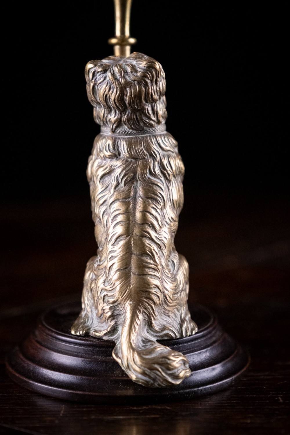 A pair of Edwardian cast brass candlesticks featuring standing terrier dogs holding tall candle columns on dark turned wooden bases. View VIII