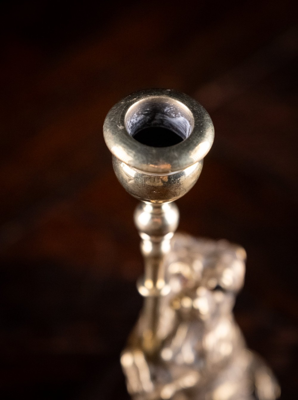 A pair of Edwardian cast brass candlesticks featuring standing terrier dogs holding tall candle columns on dark turned wooden bases. View IX