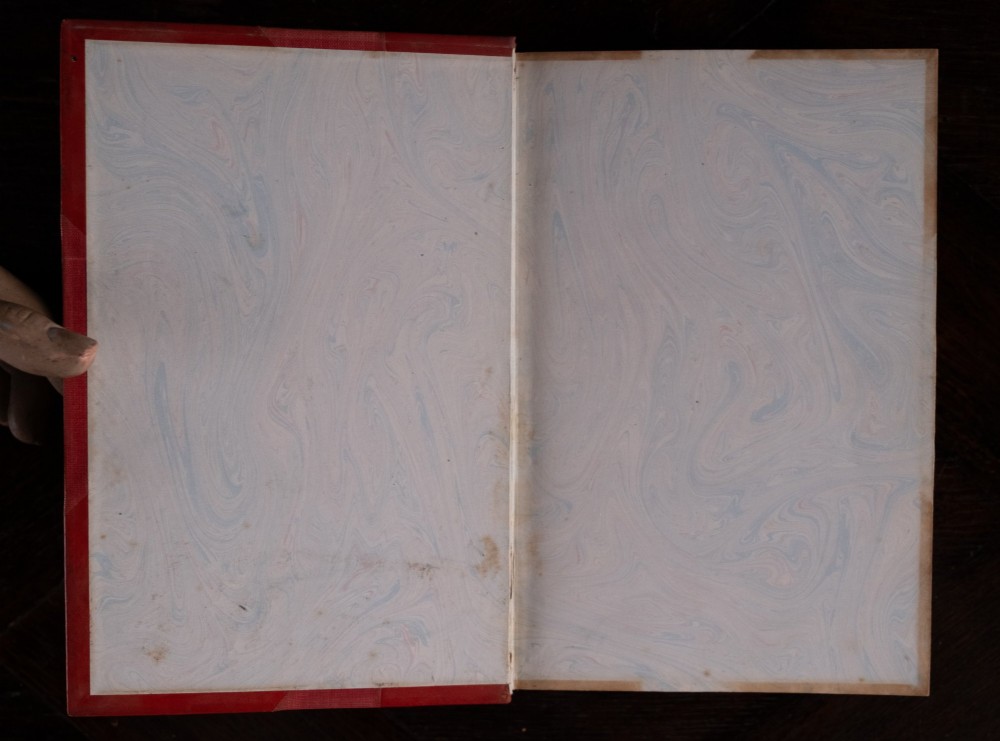 A five-volume set of red books featuring gilt spine lettering and embossed animal motifs. View VII