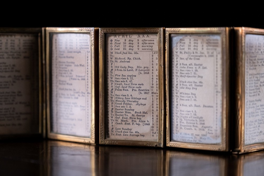 A Victorian six-panel folding brass frame holding a miniature 1878 printed London almanac. View III