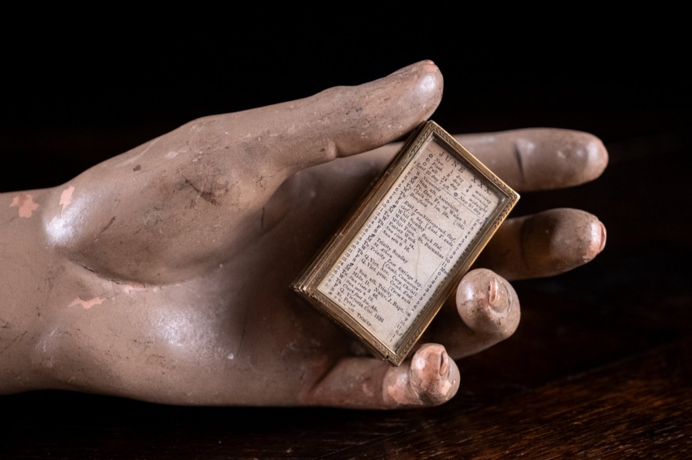 A Victorian six-panel folding brass frame holding a miniature 1878 printed London almanac. View VI