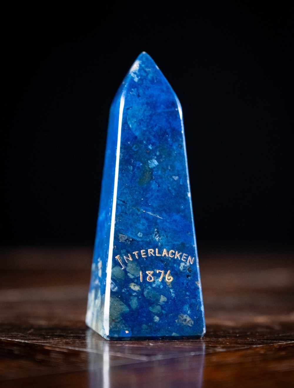 A polished deep blue lapis lazuli obelisk featuring incised gold lettering that reads Interlacken 1876.