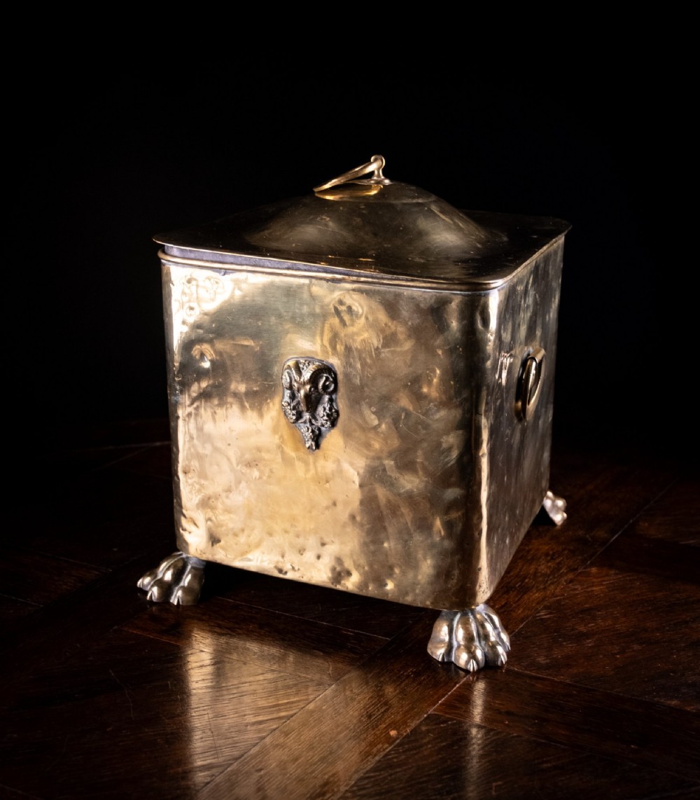 A square Victorian brass coal bin featuring a domed lid with a top ring handle, cast ram head mounts, drop ring handles, and four claw and paw feet. View III