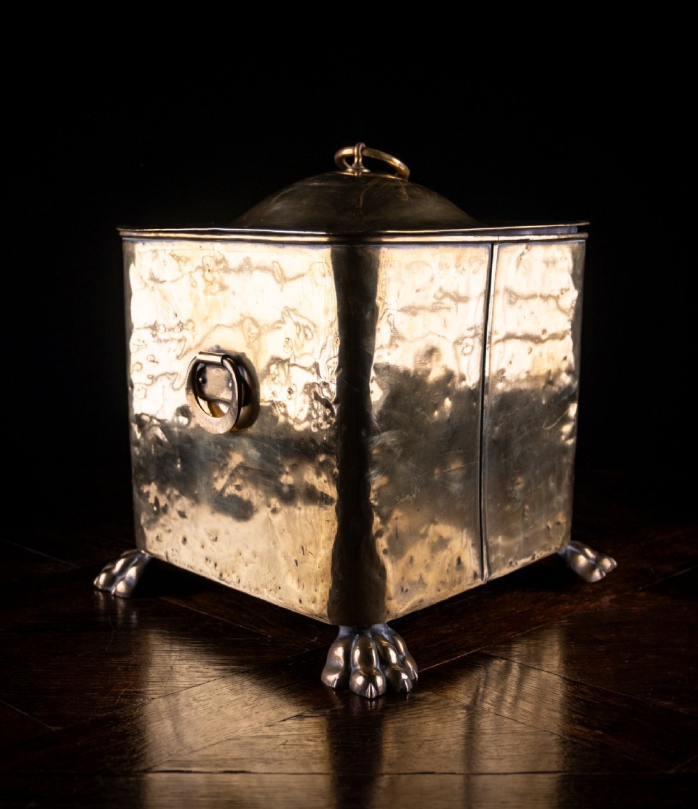 A square Victorian brass coal bin featuring a domed lid with a top ring handle, cast ram head mounts, drop ring handles, and four claw and paw feet. View VIII