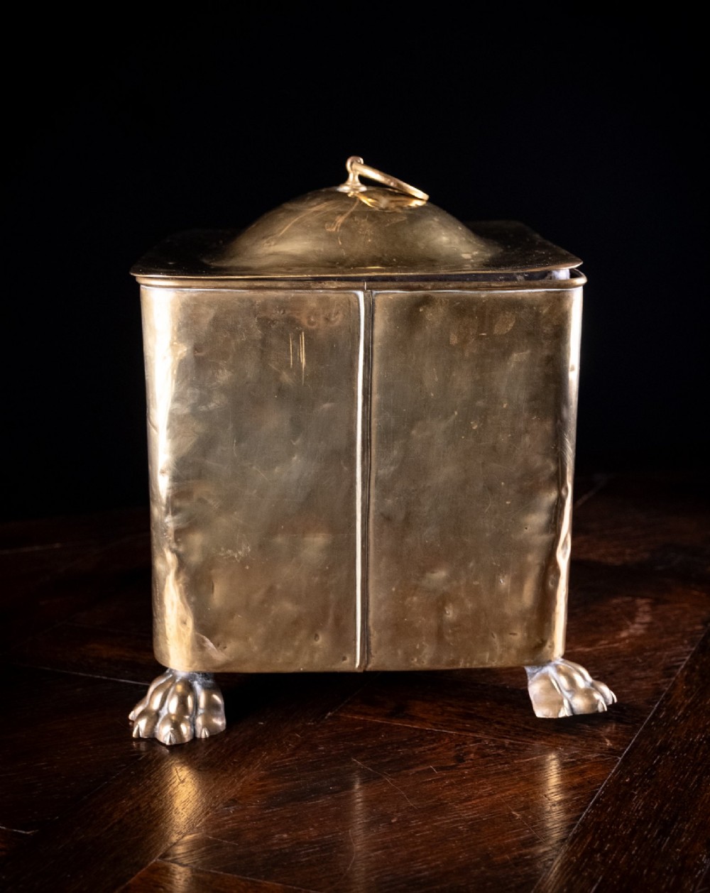 A square Victorian brass coal bin featuring a domed lid with a top ring handle, cast ram head mounts, drop ring handles, and four claw and paw feet. View IX