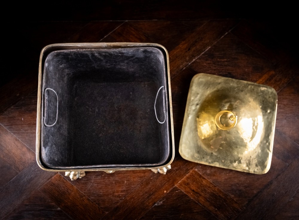 A square Victorian brass coal bin featuring a domed lid with a top ring handle, cast ram head mounts, drop ring handles, and four claw and paw feet. View XIII