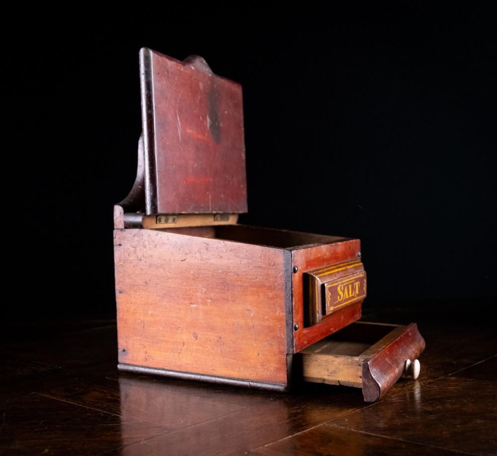 A nineteenth-century reddish-brown painted wooden wall-hanging salt box featuring gilt lettering reading SALT, a sloping hinged lid, and a small bottom drawer. View VI