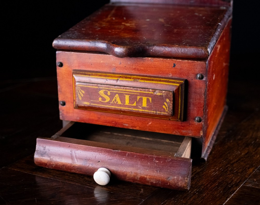 A nineteenth-century reddish-brown painted wooden wall-hanging salt box featuring gilt lettering reading SALT, a sloping hinged lid, and a small bottom drawer. View IX