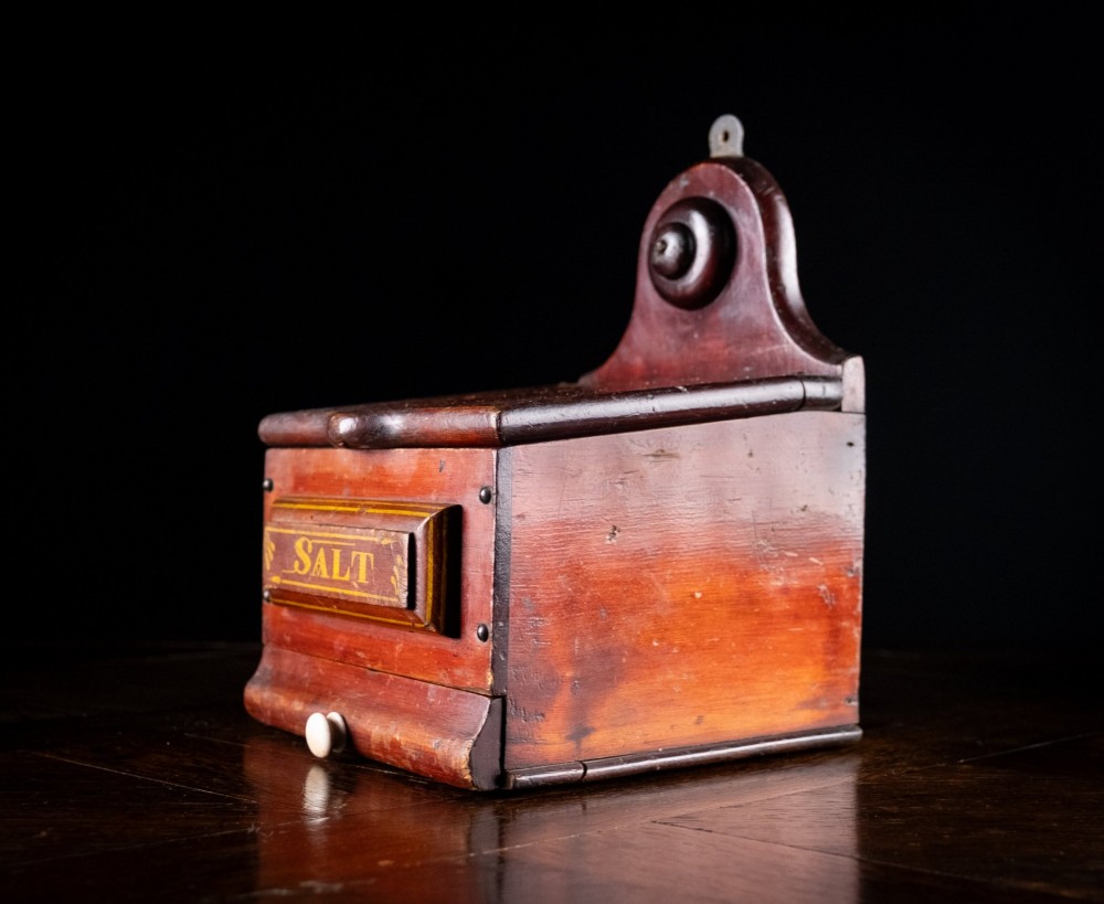 A nineteenth-century reddish-brown painted wooden wall-hanging salt box featuring gilt lettering reading SALT, a sloping hinged lid, and a small bottom drawer. View XI