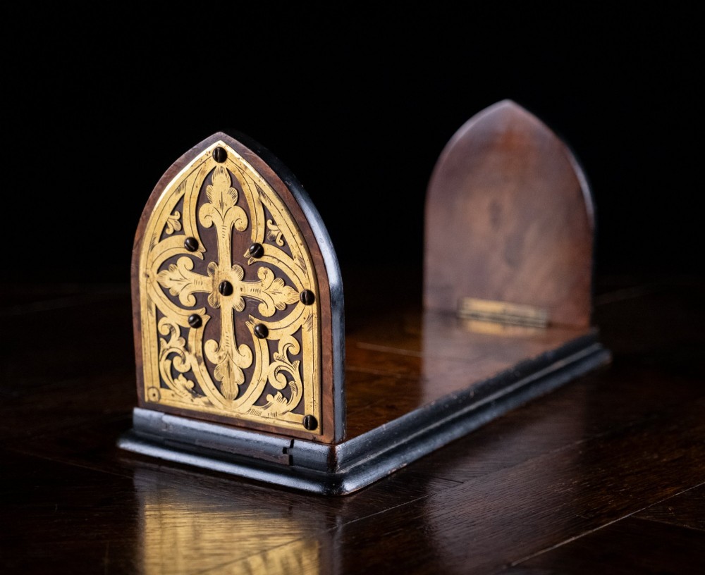 An antique dark walnut extending book slide featuring arched gothic ends detailed with pierced and engraved brass mounts.