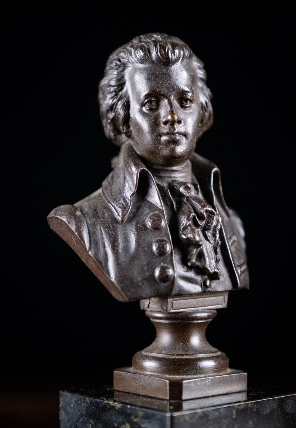 A dark patinated bronze bust of Wolfgang Amadeus Mozart mounted on a square black marble plinth. View II
