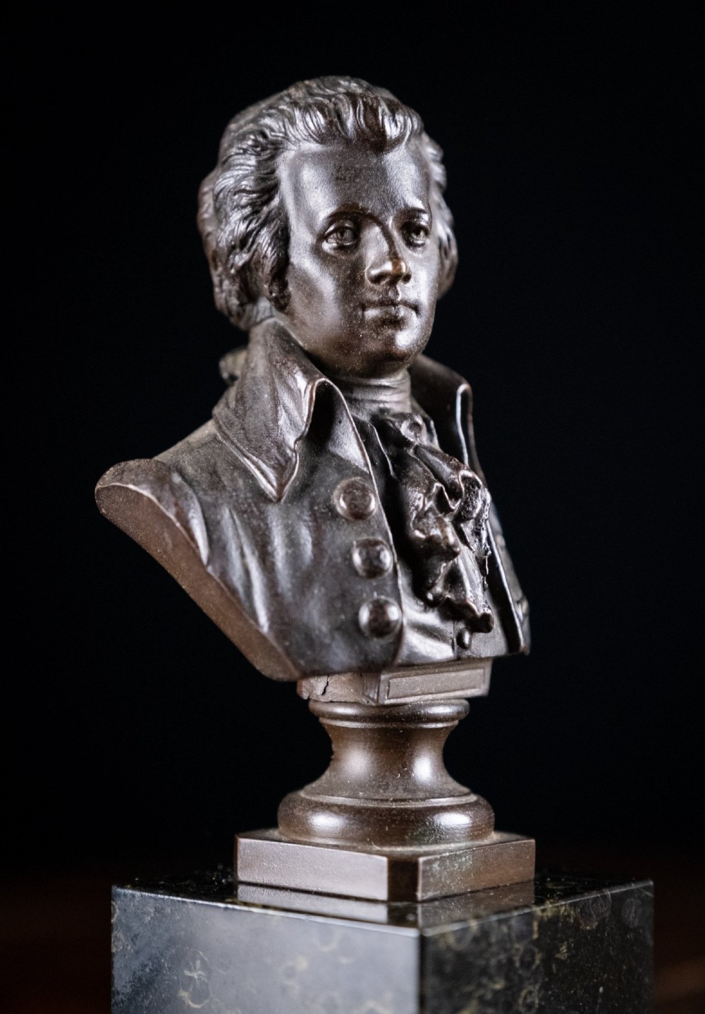 A dark patinated bronze bust of Wolfgang Amadeus Mozart mounted on a square black marble plinth. View III