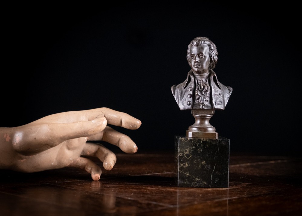 A dark patinated bronze bust of Wolfgang Amadeus Mozart mounted on a square black marble plinth. View IV