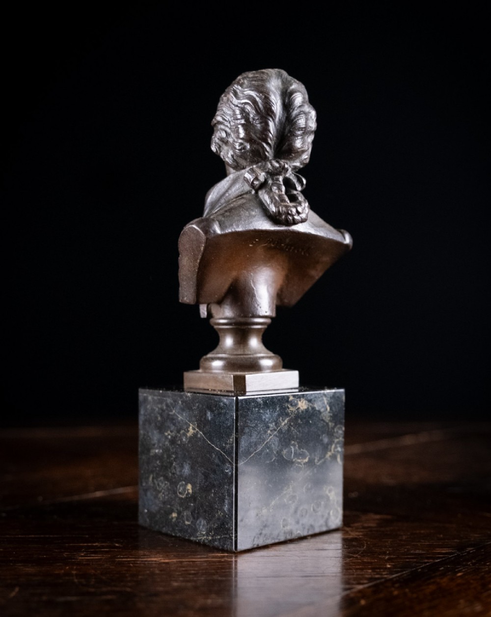 A dark patinated bronze bust of Wolfgang Amadeus Mozart mounted on a square black marble plinth. View VI